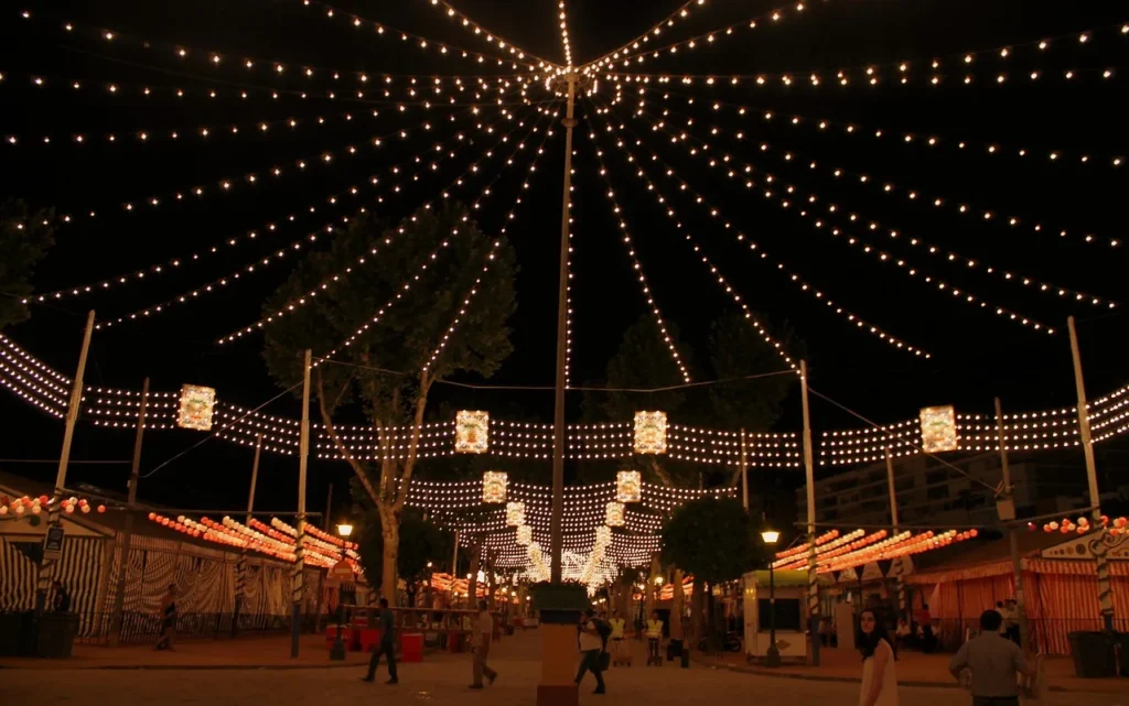 Rua do recinto da Feria de Abril com casetas e grinaldas de luzes à noite