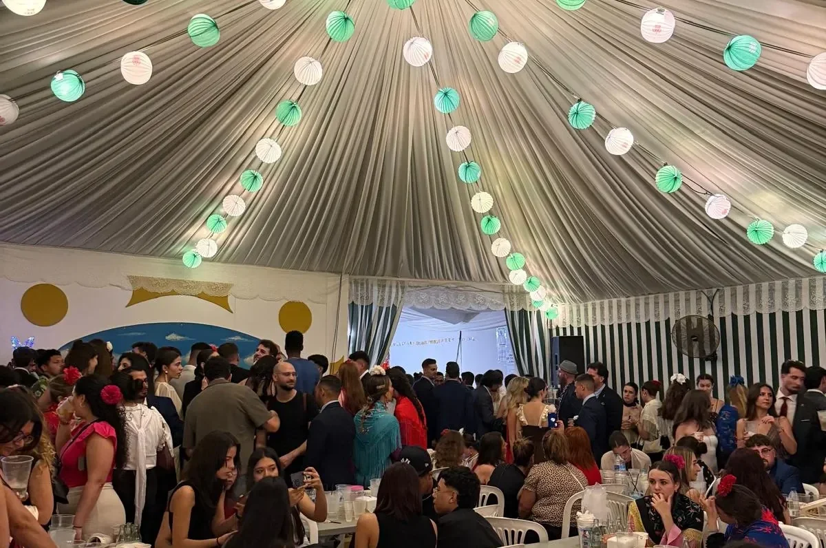 Interior de uma caseta da Feria, com mesas, visitantes e lanternas verdes e brancas