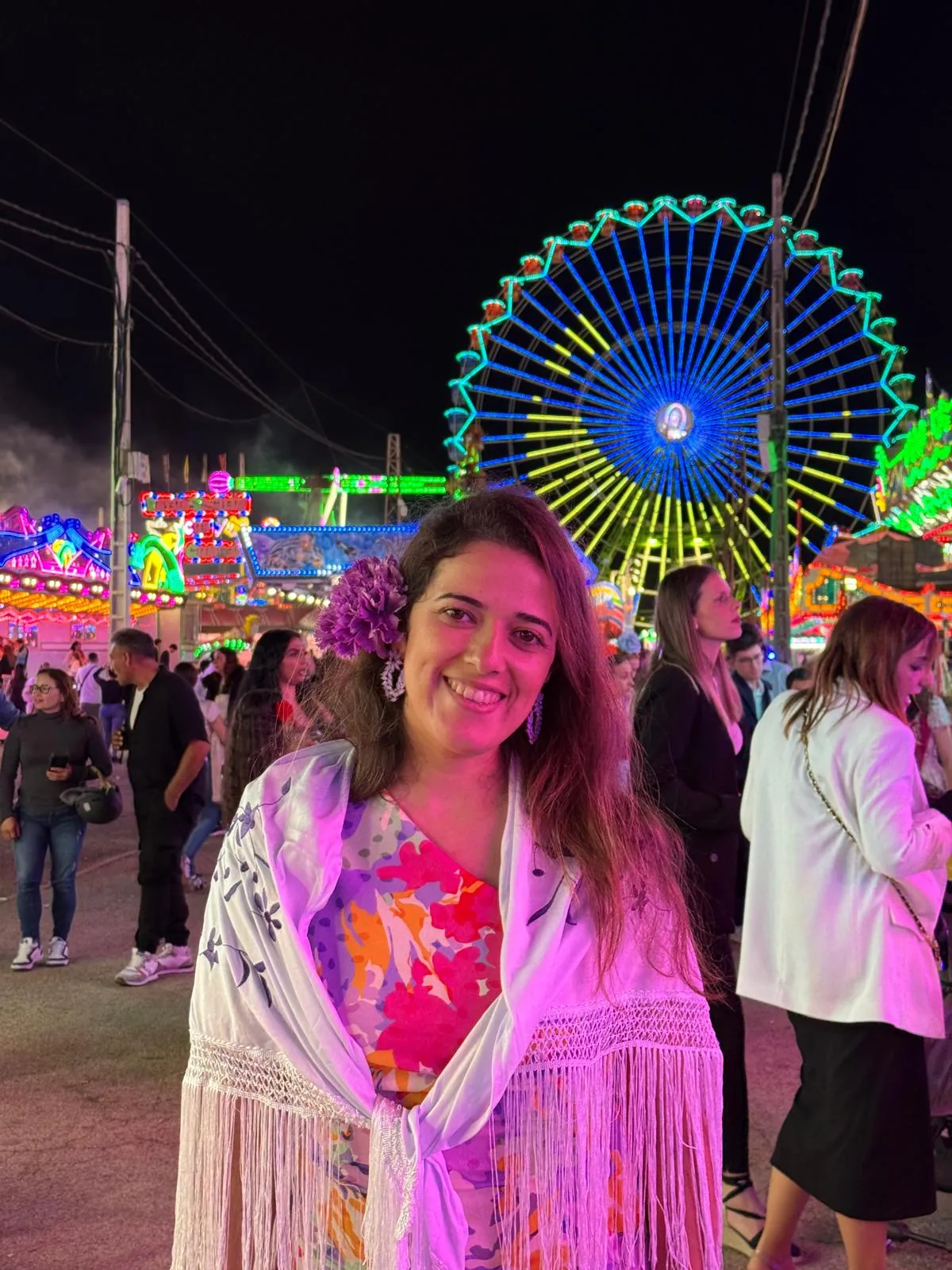 Alexandra na zona de diversões da Feria de Abril, com uma roda gigante iluminada ao fundo