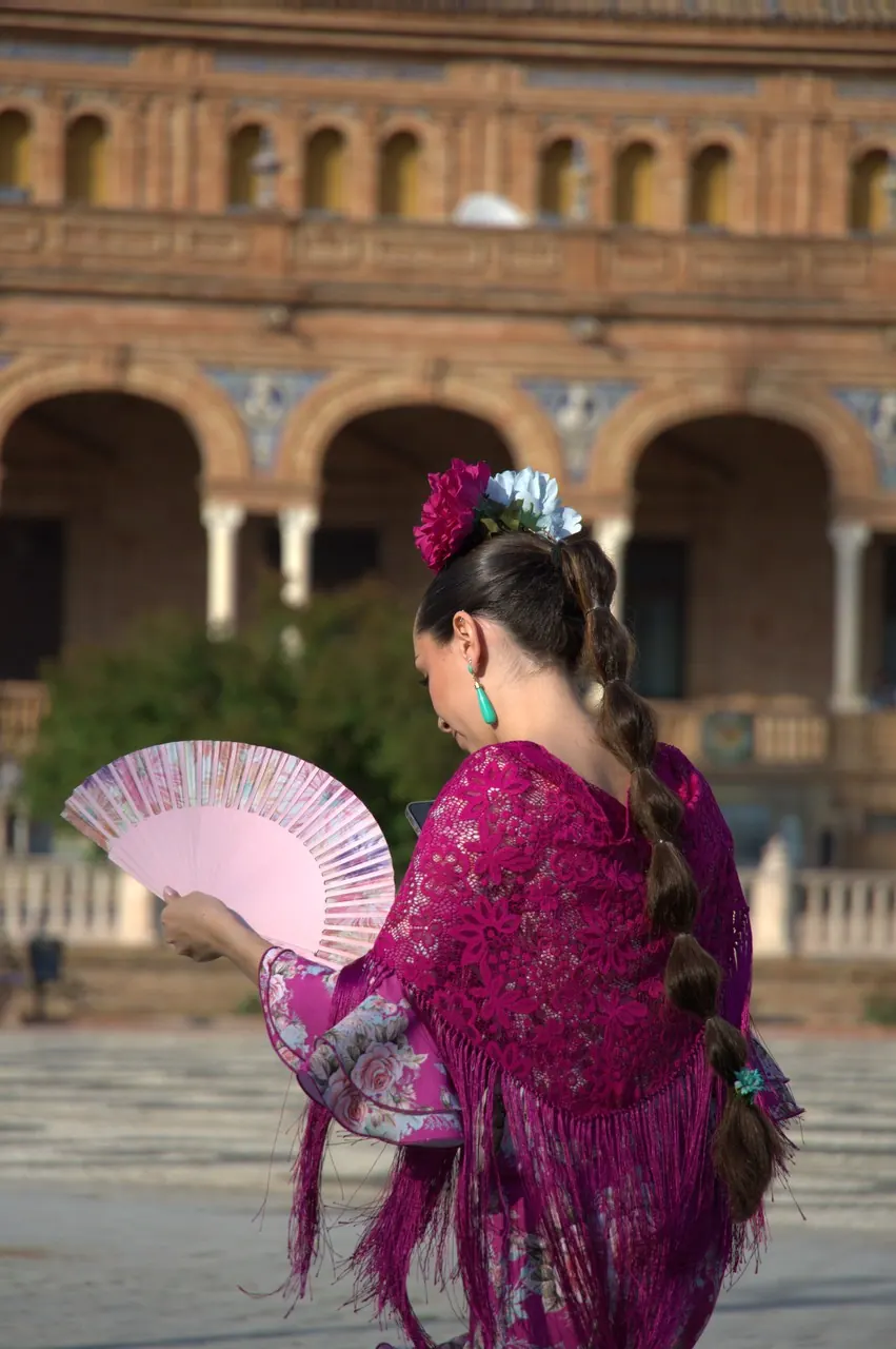 Mulher com traje de flamenca roxo e um leque junto à Plaza de España