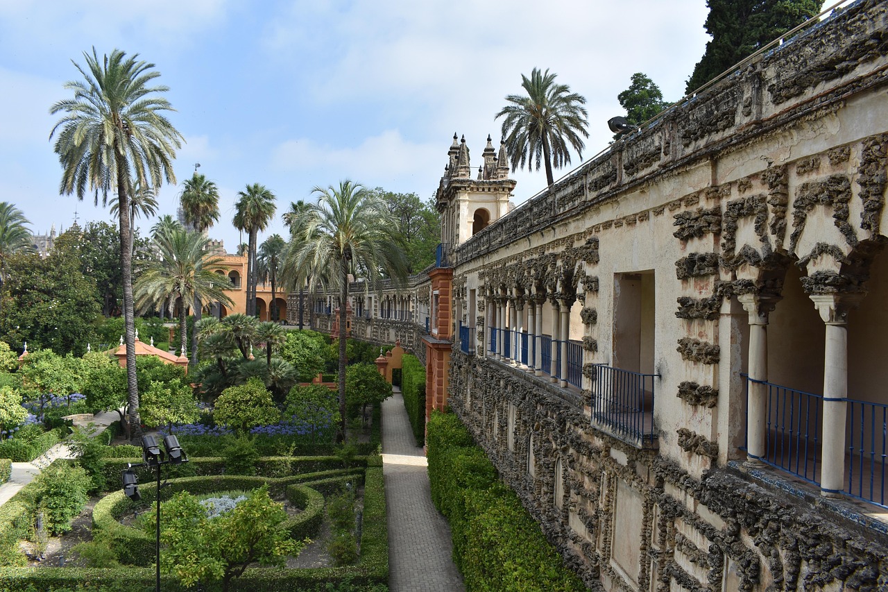 Jardins com palmeiras e galeria do Real Alcázar de Sevilha
