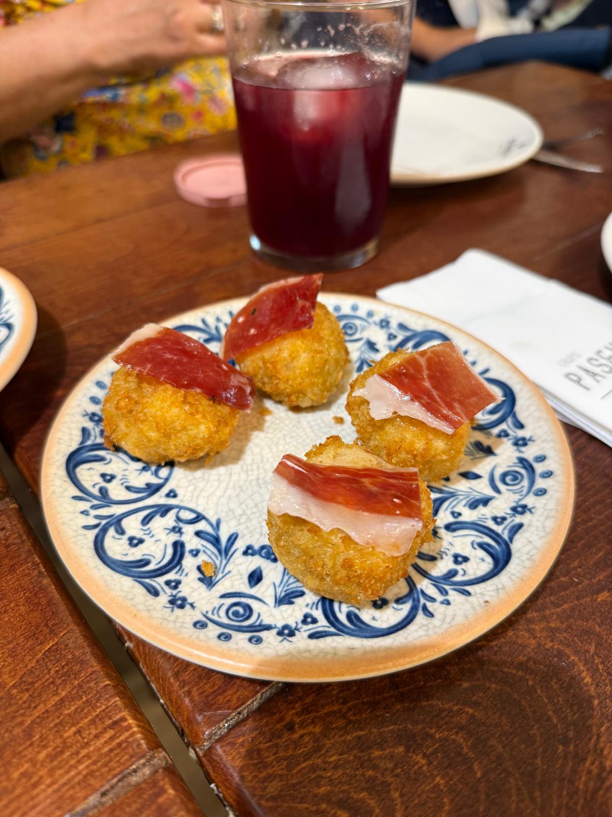 Quatro croquetes com fatias de presunto num prato de cerâmica azul e branca